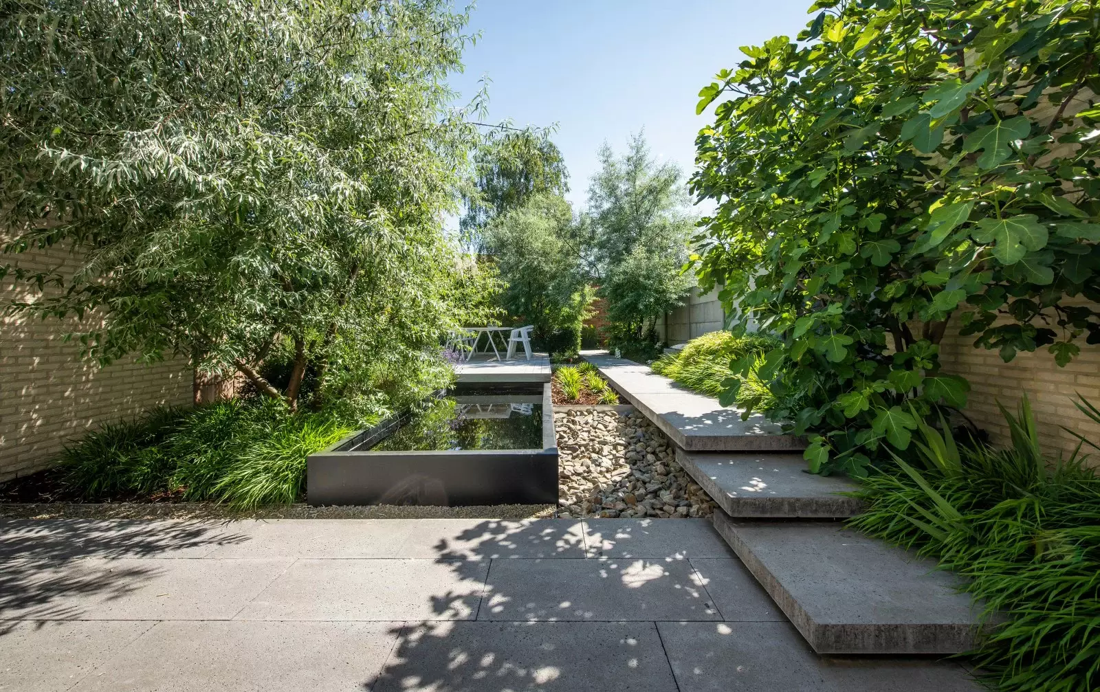 Weelderig aangelegd tuinpad met kleurrijke beplanting en siergrassen in een Vlaamse tuin